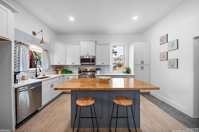 kitchen featuring white cabinetry, butcher block countertops, sink, and appliances with stainless steel finishes