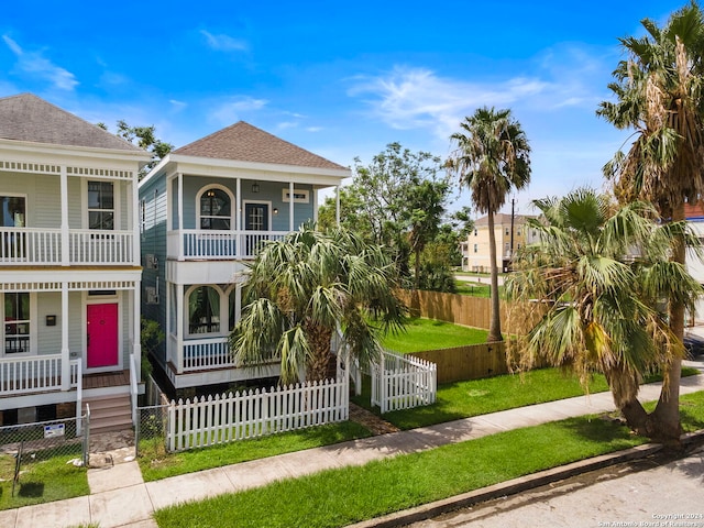 view of front of property featuring a balcony, a front yard, and covered porch