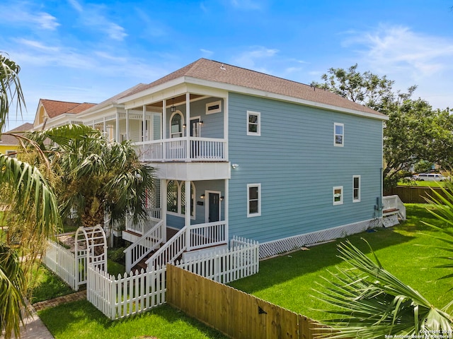 back of house with a porch, a balcony, and a lawn