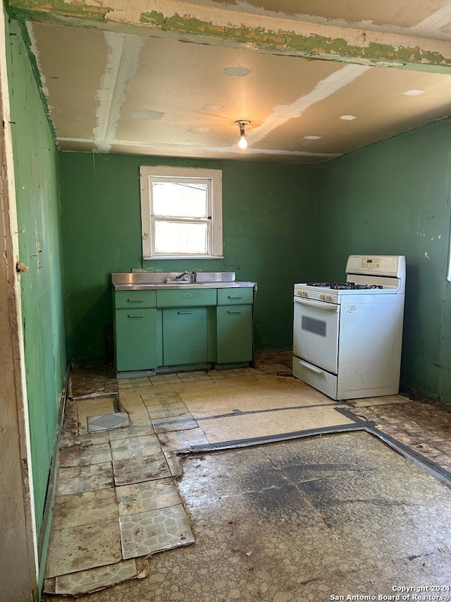 kitchen with green cabinets, sink, and white gas range