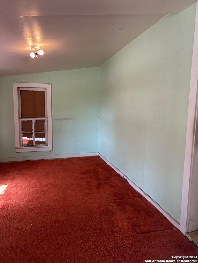 carpeted spare room featuring lofted ceiling