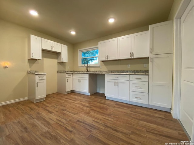 kitchen featuring sink, dark wood-type flooring, light stone counters, and white cabinetry