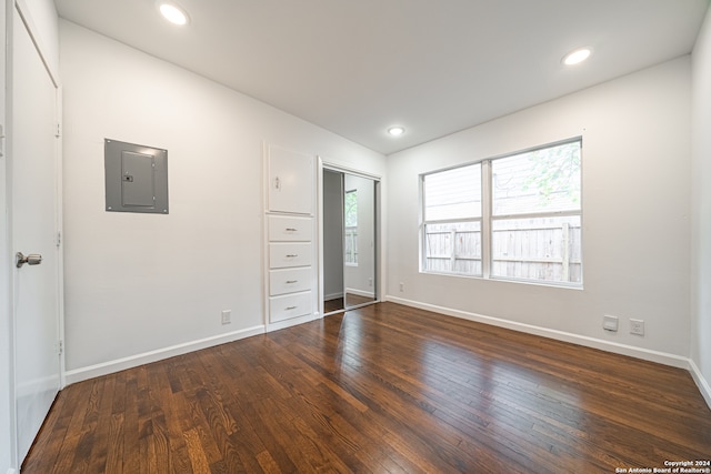 unfurnished bedroom featuring a closet, dark hardwood / wood-style flooring, electric panel, and multiple windows