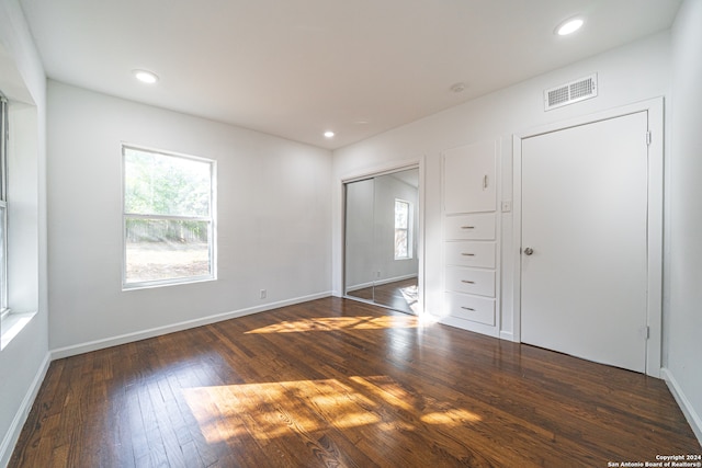 unfurnished bedroom with multiple windows and dark wood-type flooring