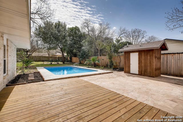 view of pool with a deck and a shed