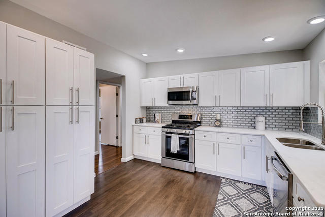 kitchen featuring sink, appliances with stainless steel finishes, tasteful backsplash, white cabinets, and dark hardwood / wood-style flooring