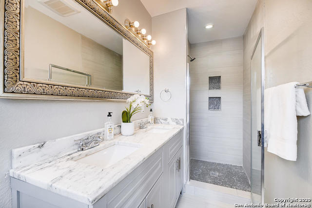 bathroom featuring vanity and tiled shower