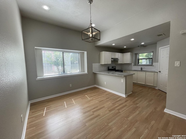 kitchen with stainless steel electric stove, pendant lighting, white cabinets, kitchen peninsula, and light wood-type flooring