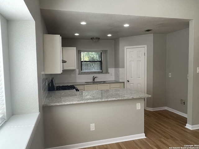 kitchen featuring white cabinetry, kitchen peninsula, sink, and stove