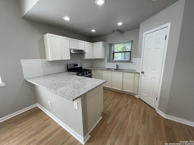 kitchen featuring stainless steel gas range, sink, white cabinetry, kitchen peninsula, and light hardwood / wood-style floors