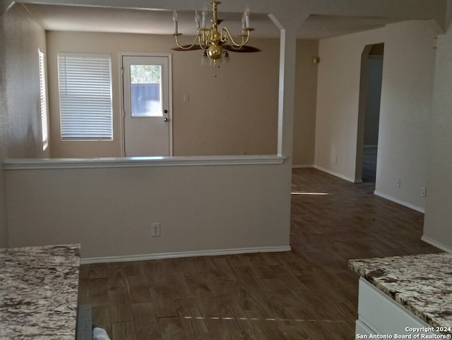 unfurnished dining area with a notable chandelier and dark wood-type flooring