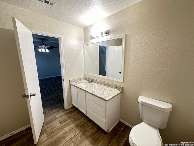 bathroom featuring a textured ceiling, toilet, vanity, ceiling fan, and wood-type flooring