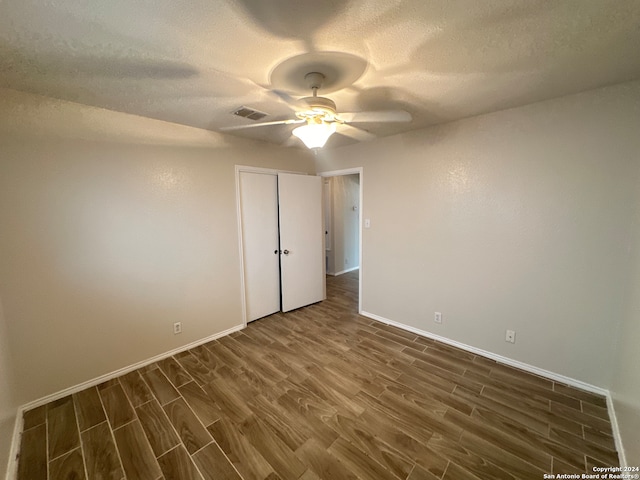 unfurnished bedroom with ceiling fan, a textured ceiling, a closet, and hardwood / wood-style floors