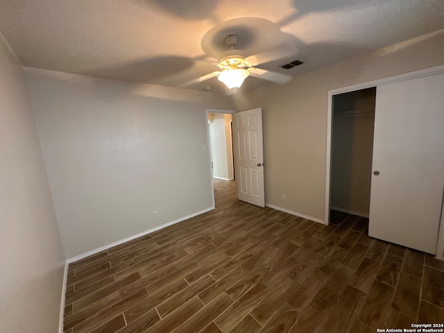 unfurnished bedroom with ceiling fan, dark hardwood / wood-style floors, a textured ceiling, and a closet