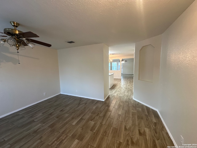 empty room with ceiling fan, dark hardwood / wood-style flooring, and a textured ceiling