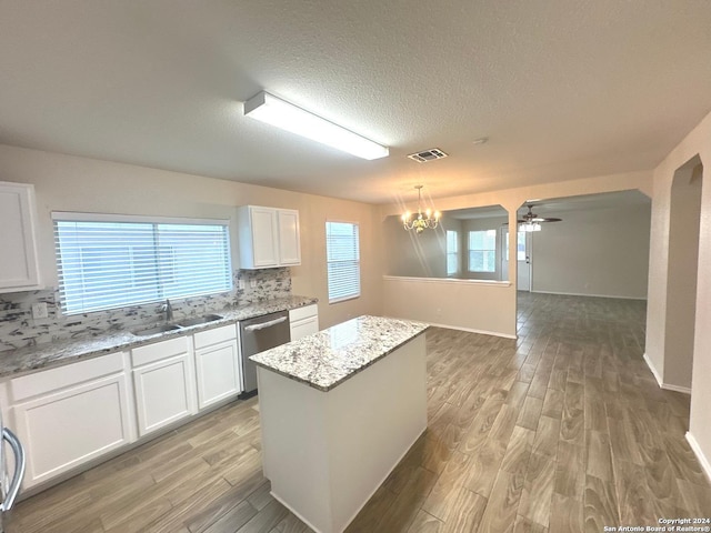 kitchen with sink, a center island, light stone counters, white cabinets, and stainless steel dishwasher