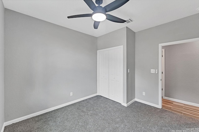 unfurnished bedroom with ceiling fan, dark carpet, and a closet