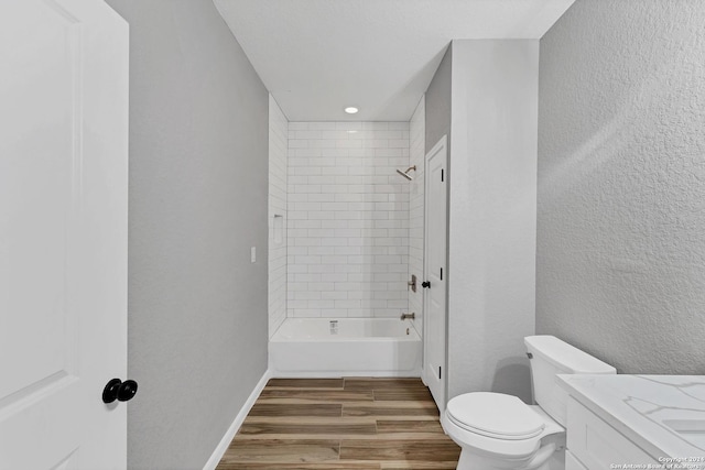 full bathroom featuring wood-type flooring, toilet, tiled shower / bath combo, and vanity