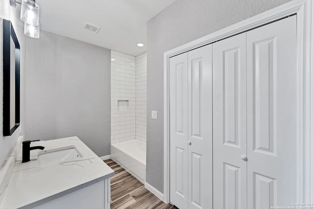 bathroom featuring vanity, hardwood / wood-style floors, and tiled shower / bath