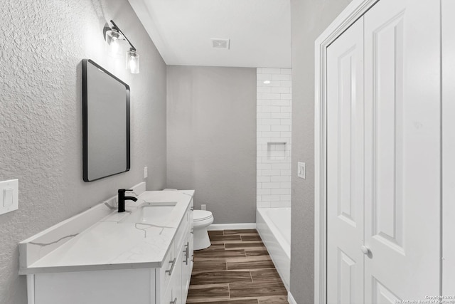 full bathroom featuring vanity, tiled shower / bath combo, and toilet