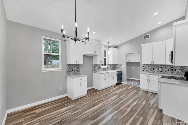 kitchen with vaulted ceiling, dark hardwood / wood-style floors, decorative light fixtures, white cabinets, and stainless steel appliances