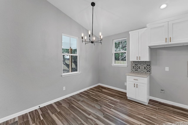 unfurnished dining area featuring lofted ceiling, dark wood-type flooring, and a notable chandelier