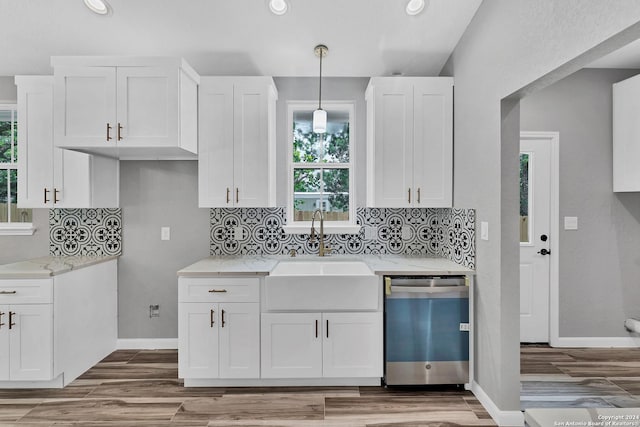 kitchen featuring sink, white cabinetry, stainless steel dishwasher, pendant lighting, and backsplash