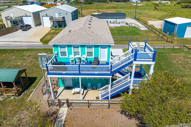 rear view of house featuring a garage, a storage unit, a wooden deck, and a lawn