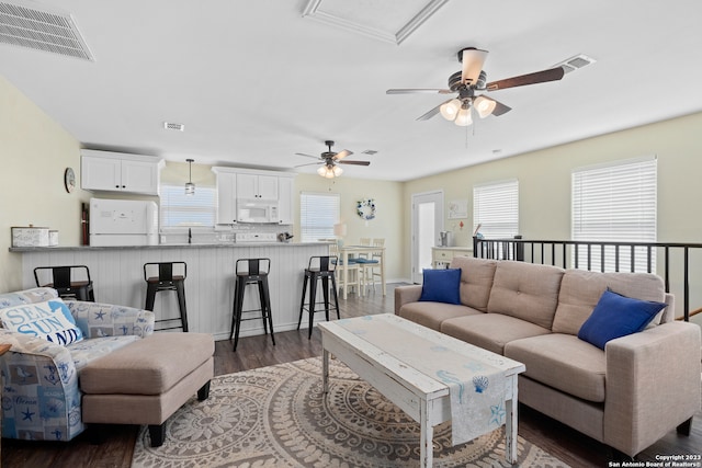 living room featuring a healthy amount of sunlight, ceiling fan, and dark hardwood / wood-style floors