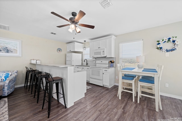 kitchen featuring white cabinetry, dark hardwood / wood-style flooring, kitchen peninsula, and white appliances