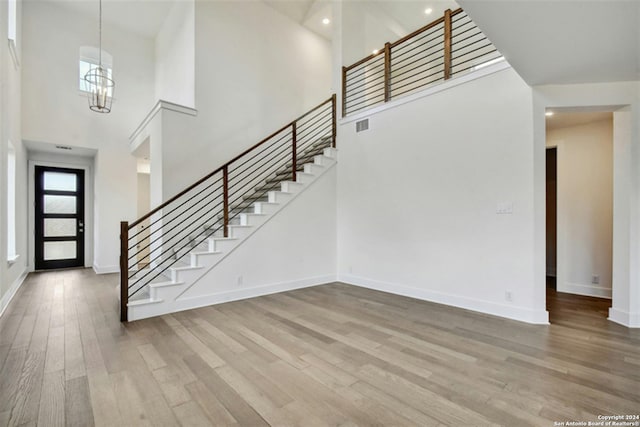 foyer entrance with wood-type flooring, a chandelier, and a high ceiling