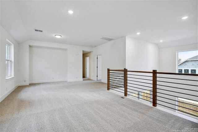 carpeted spare room with vaulted ceiling