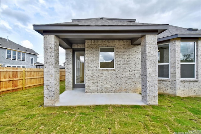 back of house with a patio area and a lawn