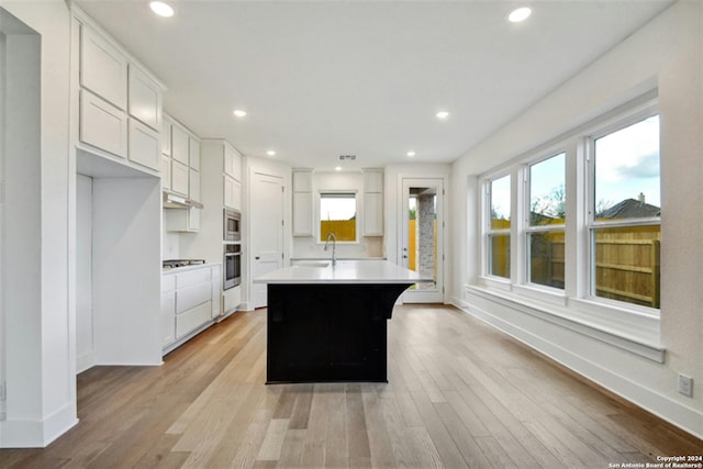 kitchen featuring stainless steel appliances, white cabinetry, a kitchen island, and light hardwood / wood-style flooring