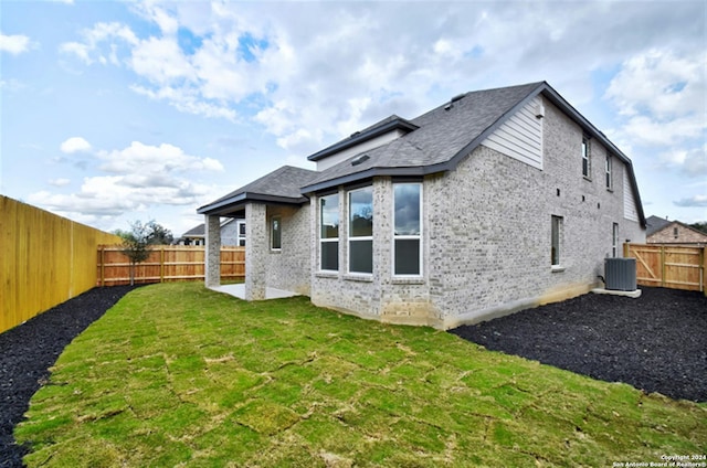 back of house featuring a yard and central AC unit