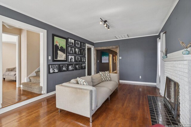 living room featuring track lighting, a brick fireplace, and dark wood-type flooring