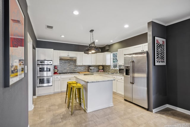 kitchen featuring appliances with stainless steel finishes, white cabinetry, a center island, and tasteful backsplash