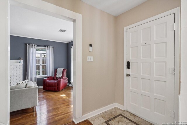 foyer entrance featuring ornamental molding and hardwood / wood-style floors