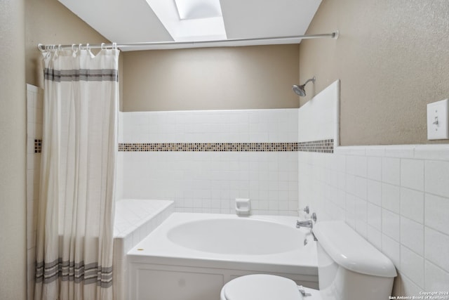 bathroom featuring a skylight, tile walls, and toilet