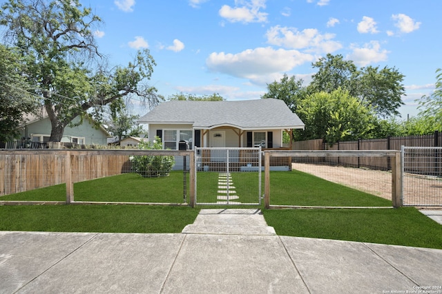 view of front of house with a fenced front yard, a gate, a shingled roof, and a front lawn