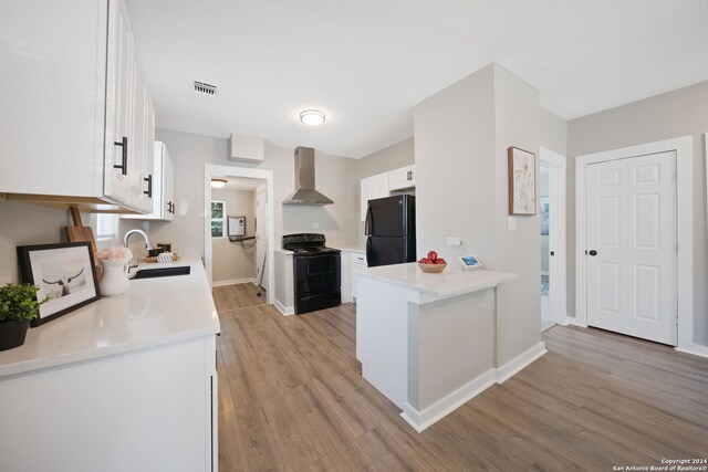 kitchen with black appliances, sink, light hardwood / wood-style floors, and wall chimney range hood