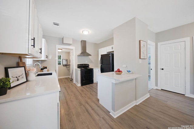 kitchen featuring light countertops, white cabinets, a sink, wall chimney range hood, and black appliances