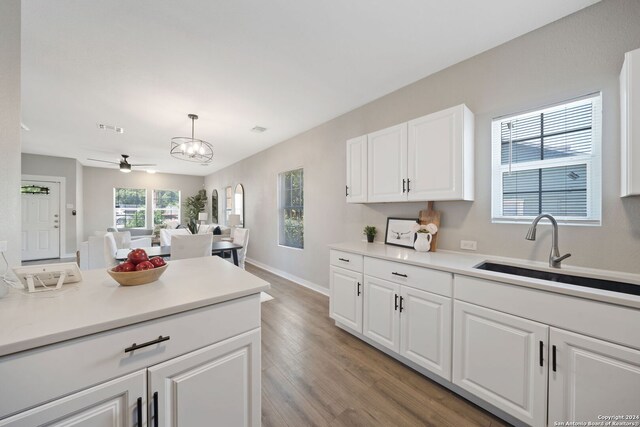 kitchen featuring pendant lighting, ceiling fan, sink, white cabinetry, and light hardwood / wood-style flooring