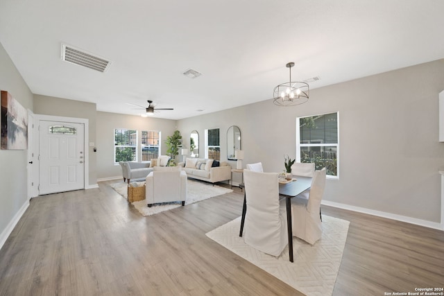 dining space featuring ceiling fan with notable chandelier and light hardwood / wood-style floors