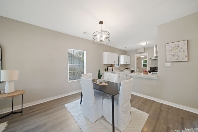 dining room with hardwood / wood-style floors, sink, a notable chandelier, and a healthy amount of sunlight