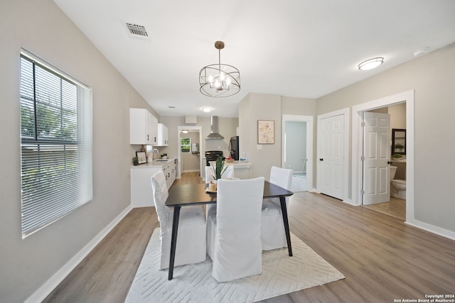 dining area with light hardwood / wood-style flooring, sink, and an inviting chandelier