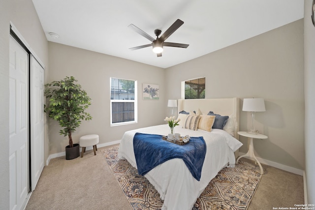 bedroom featuring ceiling fan, light carpet, and a closet