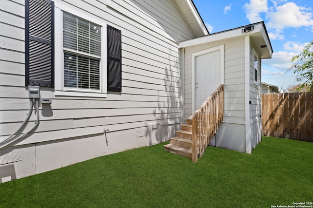 property entrance with crawl space, fence, and a lawn