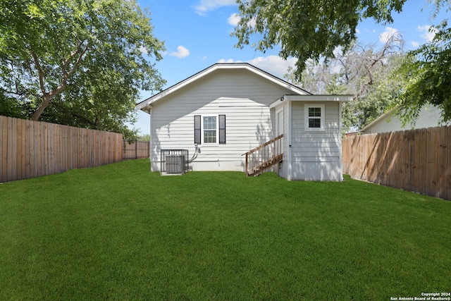 back of property with central AC and a yard