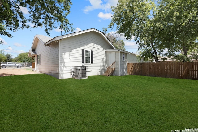 back of house with entry steps, fence, and a lawn